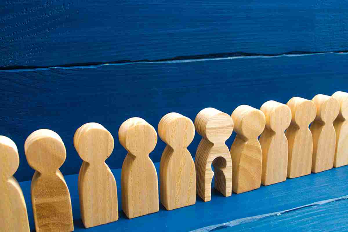 Holzfiguren in einer Reihe, eine hat ein ausgeschnittenes Kind